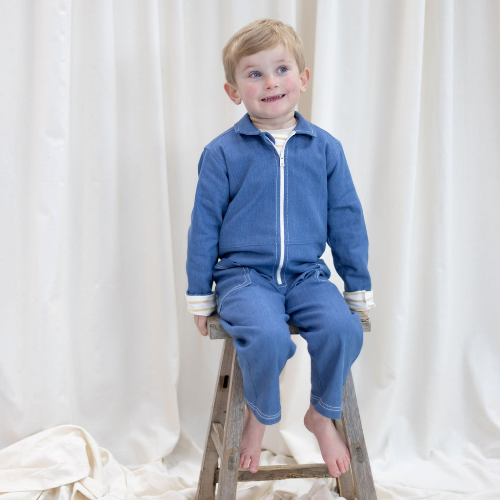 Blue recycled denim  jumpsuit with long ecru chunky teeth zip down the front.  2 big pockets on hips topstitched with ecru thread.  Long sleeves and leg length mean piece will last through growth spurts
