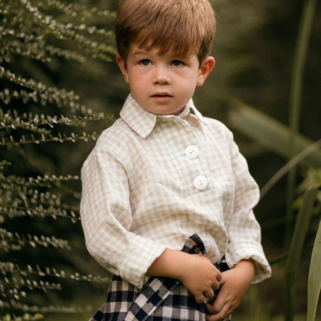 Unisex kids shirt made from beige linen gingham check.  Large offwhite button opening and sleeves that can be rolled up.  Worn with blue brushed gingham cotton and wool trousers with detachable braces