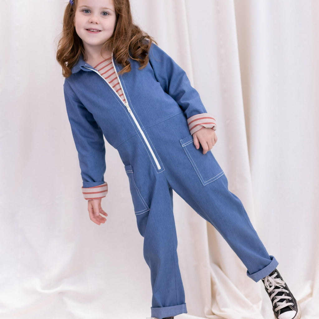 Blue recycled denim  jumpsuit with long ecru chunky teeth zip down the front.  2 big pockets on hips topstitched with ecru thread.  Long sleeves and leg length mean piece will last through growth spurts