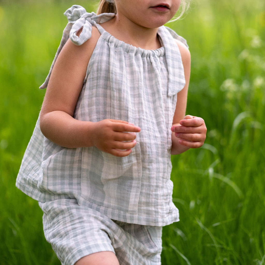 Child wearing the girls Maya mint gingham swing top with bow tie shoulder detail worn with the kids unisex Merin shorts in mint gingham