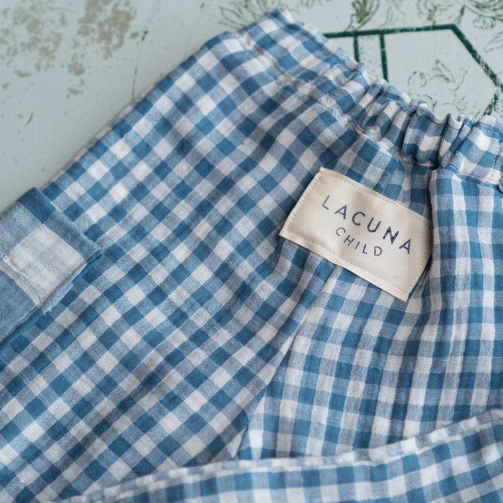 Back view of the Quinn kids culottes in blue gingham showing the gathered elastic waist and ecru cotton label with the words Lacuna Child printed on