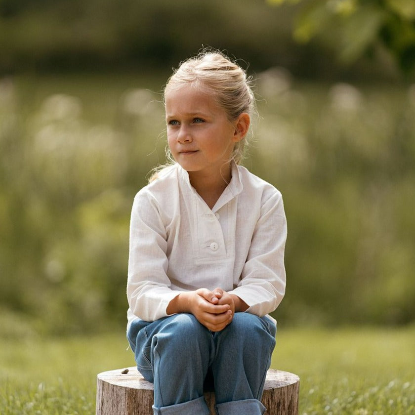 Made from organic cotton and hemp this offwhite unisex kids shirt is a wardrobe staple.  Opens with offwhite buttons and generously cut to be oversized and sleeves that can be rolled up.  Worn with childrens unisex recycled blue denim jeans