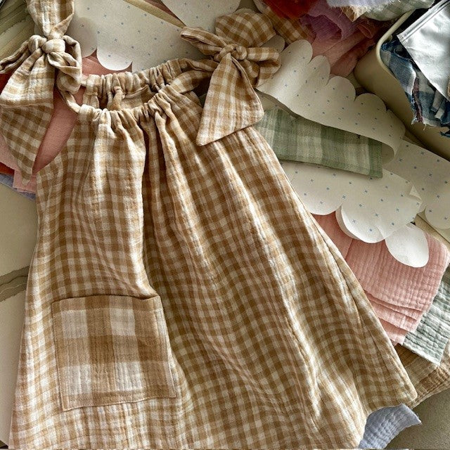 Beige gingham girls dress with gathered neckline and bow shoulder ties