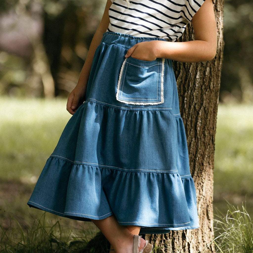 Made from recycled denim the blue girls skirt is made to wear all year round.  Add a large pocket edged with offwhite cotton scallop trim.  Worn with a sleeveless blue striped unisex Breton top