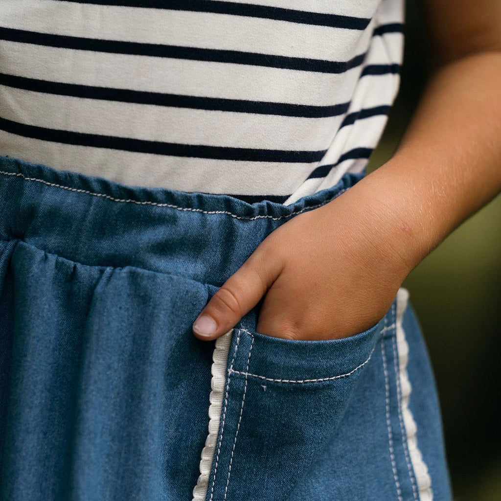 Beautiful recycled blue denim childs skirt featuring an oversized pocket edged with an offwhite cotton scallop trim.  Worn with a kids unisex sleeveless blue stripe Breton top