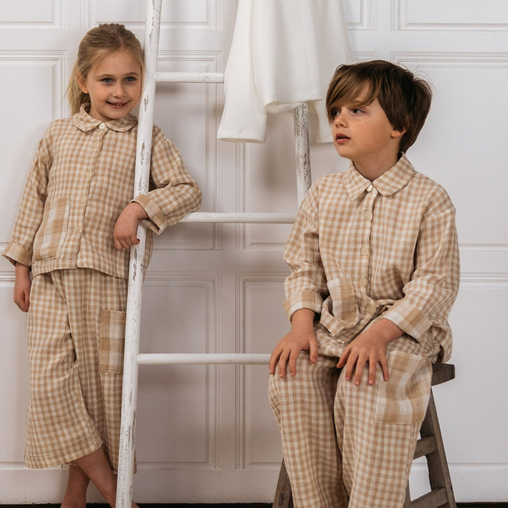 Girl and boy wearing the Bailey sand gingham check childrens shirt with rolled up sleeves and oversize pockets.   Worn with the Marlow sand gingham check unisex kids culottes